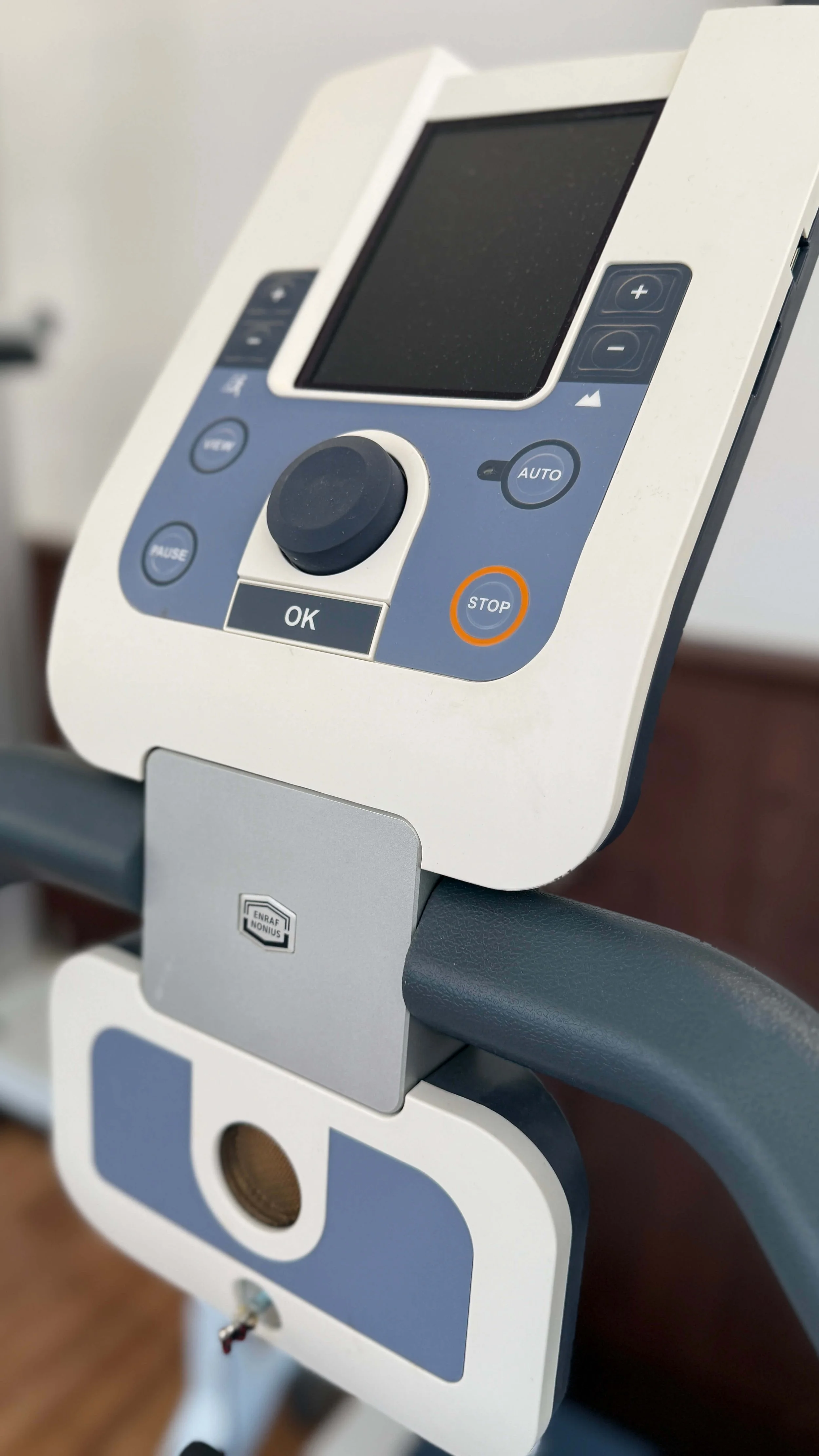 Medizinisches Gerät, wahrscheinlich ein EKG-Gerät mit Bildschirm, Tasten und Steuerknüppel, auf einem Rollwagen.